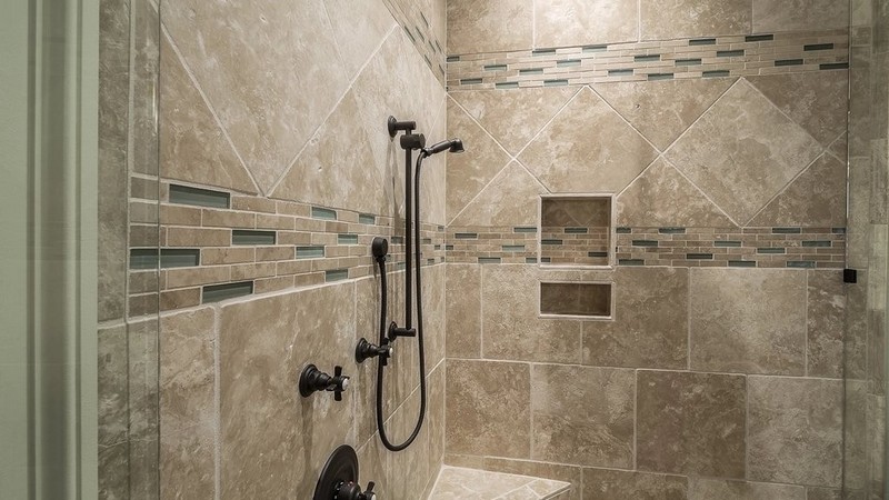 Une douche en tuiles effet travertin, avec niche encastrée et bande de mosaïque. Photo : rawpixel (CC0).